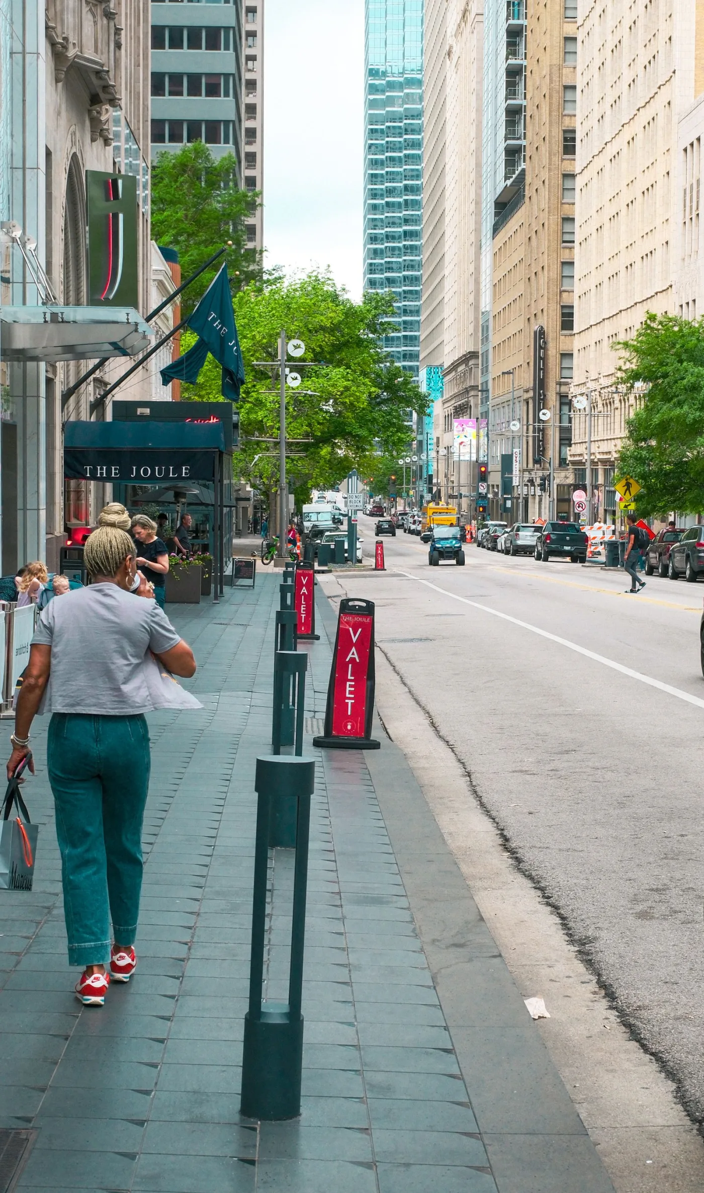 A resident walking through a sunny city street